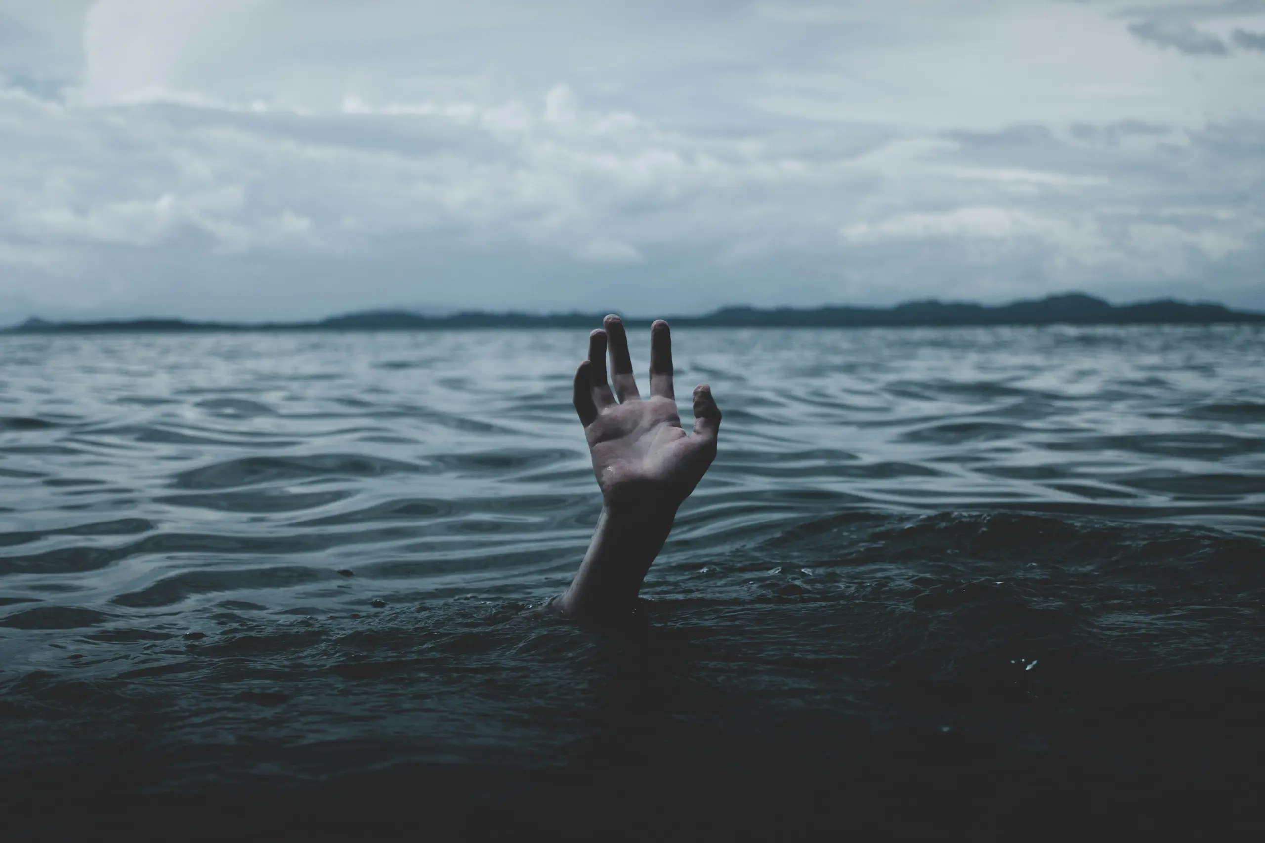 An image of a hand above the water line, its body submerged